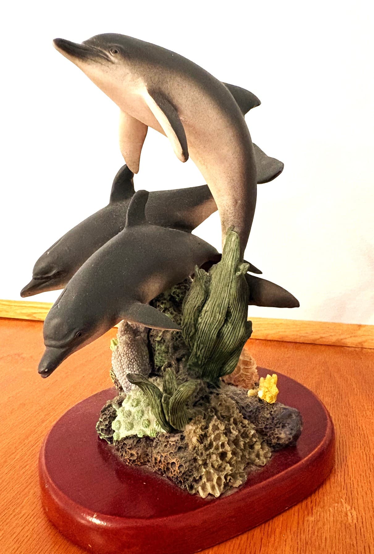 An interior view of a white wicker vanity table featuring a lit vintage-style floral lamp, an open guest book with a pen, and several travel brochures. To the left, a matching white wicker-framed mirror reflects the lamp's warm glow.