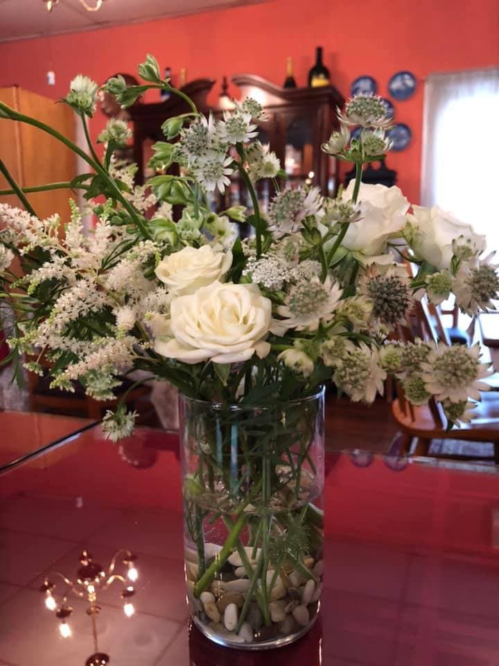 A bouquet of white flowers in a clear vase filled with pebbles.
