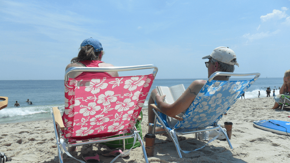 A couple relaxes in colorful beach chairs while enjoying the ocean view.