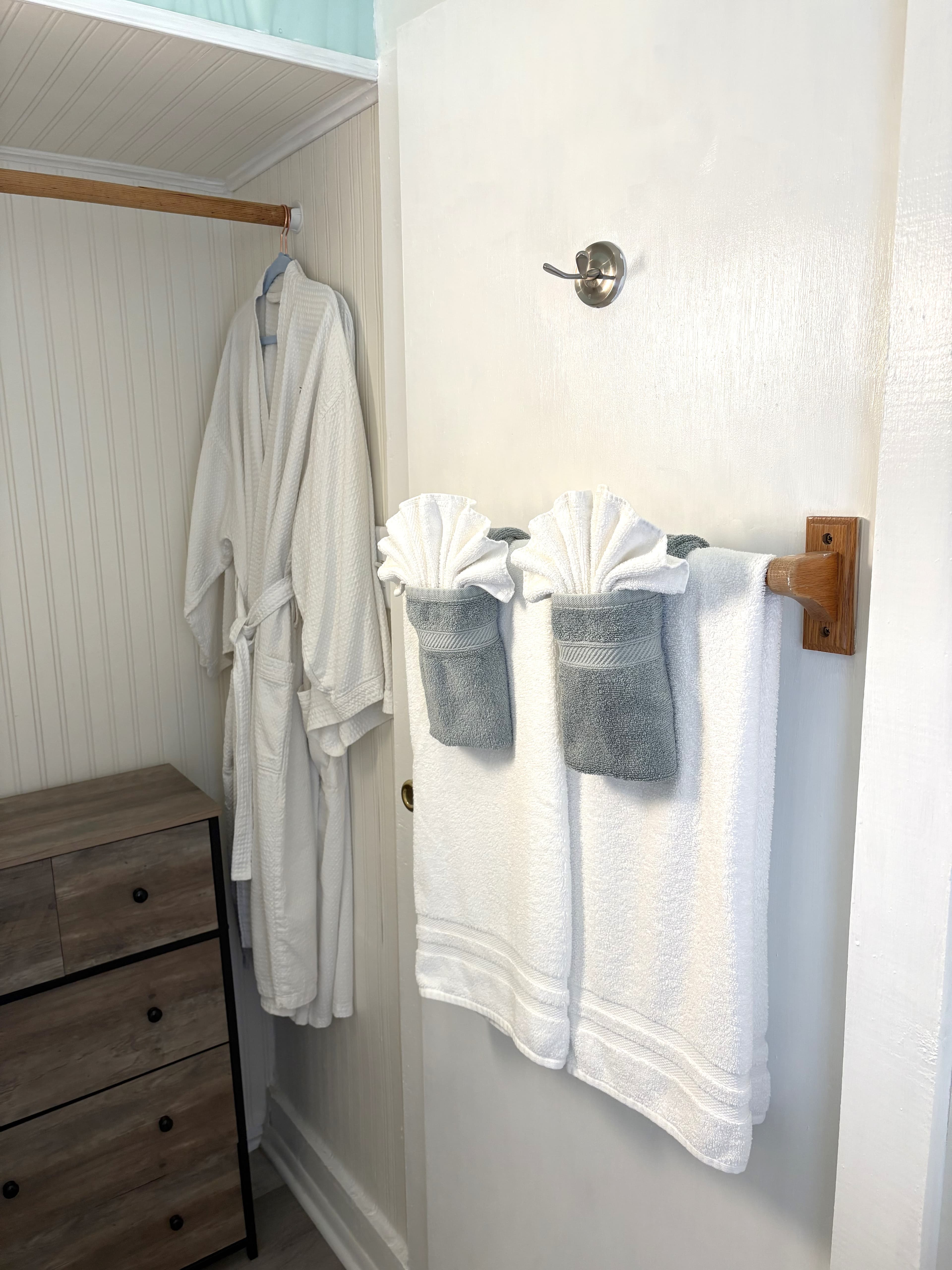A cozy bathroom scene featuring a bathrobe hanging beside neatly arranged folded towels on a door.