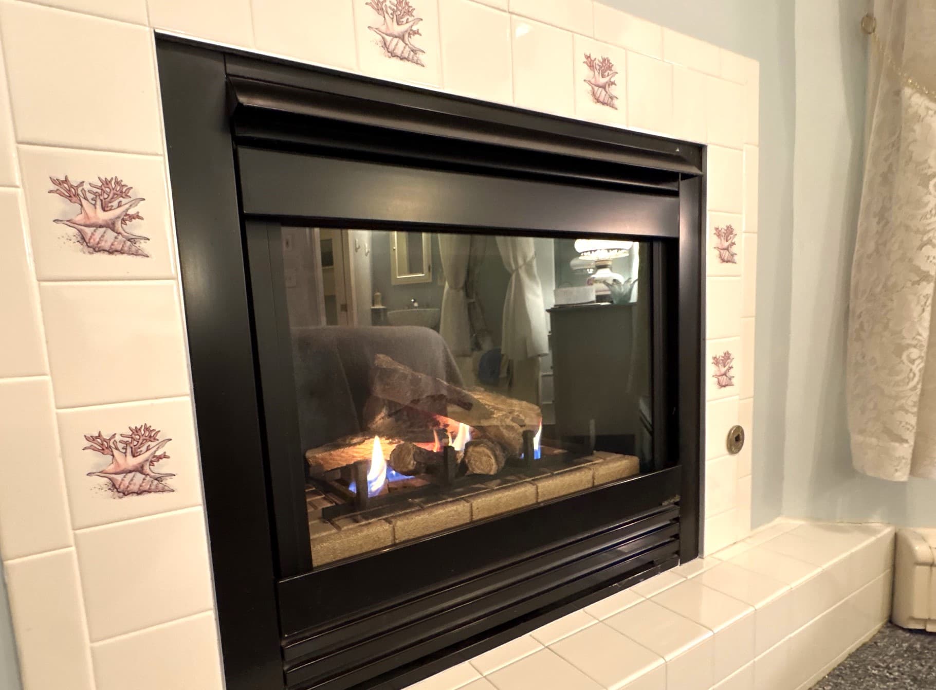 A modern gas fireplace with a black frame and decorative tiled surround displaying a small flame.
