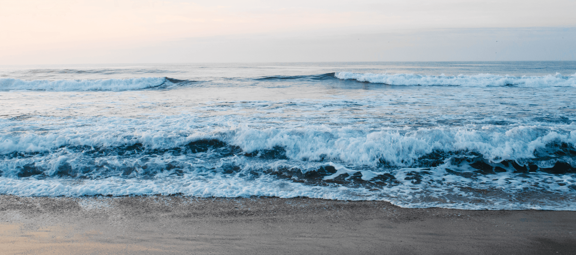 Waves gently lap against the shore under a serene sky.